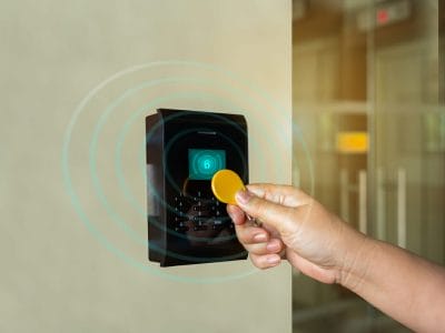 A door access control system. young person holding a key card to lock and unlock door to entry building is security system.